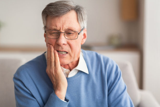 caring for tooth sensitivity a man holds his jaw and wonders about caring for tooth sensitivity