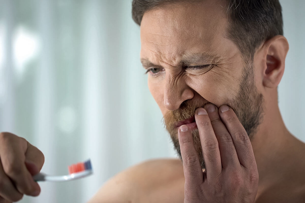 gingivitis, gum disease man struggles with the pain caused by gingivitis