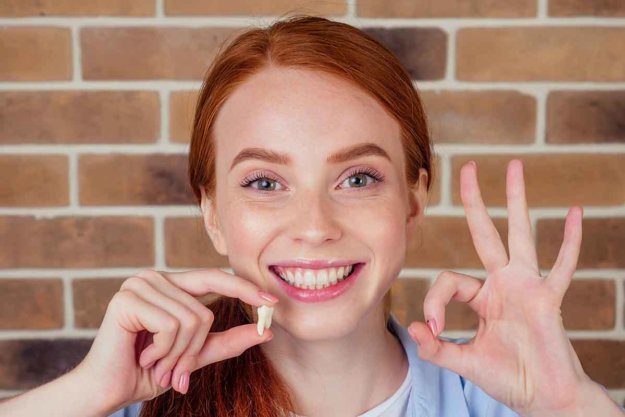 What You Should Know After Wisdom Teeth Removal girl holding tooth after wisdom teeth removal