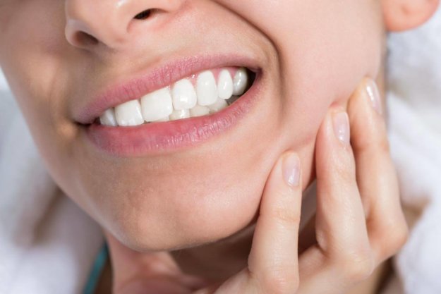 Common Causes of Dental Trauma a woman holding her mouth wondering the common causes of dental trauma
