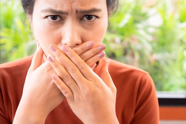 How to Fix Bad Breath person covers up mouth while trying to fix bad breath