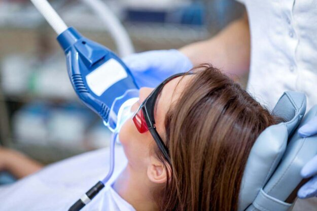 How Long Does Teeth Whitening Last woman receives teeth whitening and talks to her dentist about teeth whitening duration
