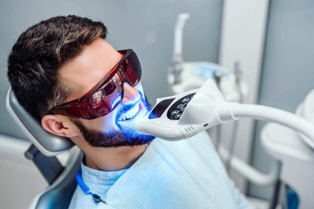 Is it Better to Get Your Teeth Whitened at the Dentist or at Home_ man receives a teeth whitening service in office
