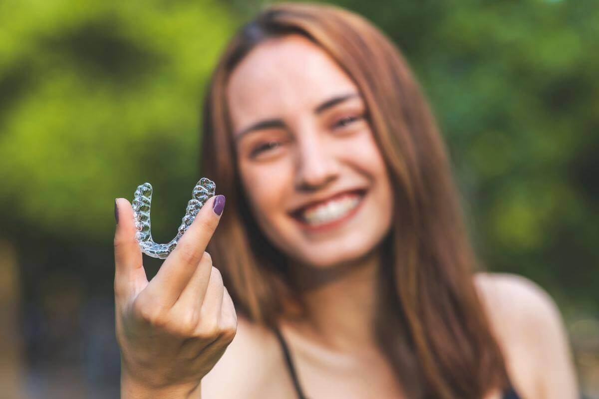 Where can I find Invisalign in Columbia, MD_ woman holds up invisalign retainer and considers where to find invisalign in columbia md